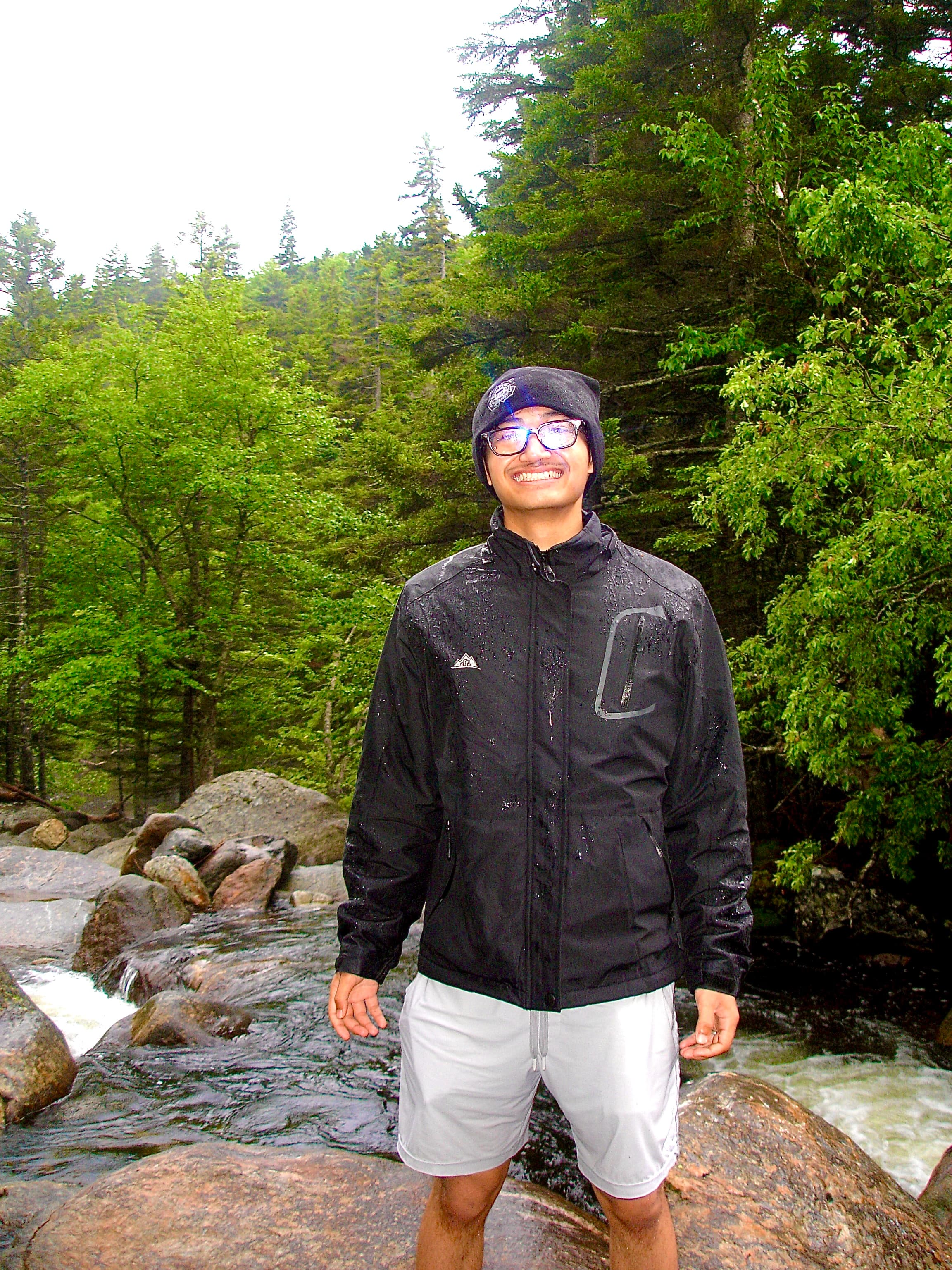 Ihsan Tjahyono on a rock beside a river in the rain